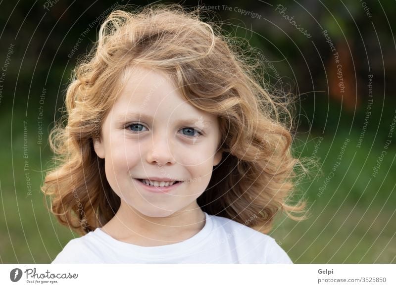Lustiges blondes Kind mit langen Haaren. außerhalb eine Kindheit Menschen Kaukasier Freude Junge wenig Natur Behaarung wellig spielen Sommer jung im Freien Spaß