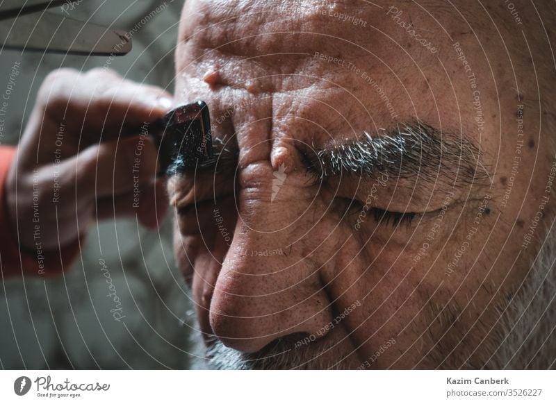 Älterer lässt sich im Badezimmer die Augenbraue stutzen Mann Kopf Vollbart Behaarung Damenbart Person Gesicht Holunderbusch alt Menschen älter Stirn Erwachsener