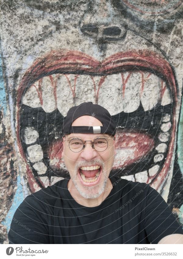 Ein schreiender Mann vor einem Graffiti Erwachsene Mensch Bart Kopf maskulin Brille Gesicht Blick in die Kamera