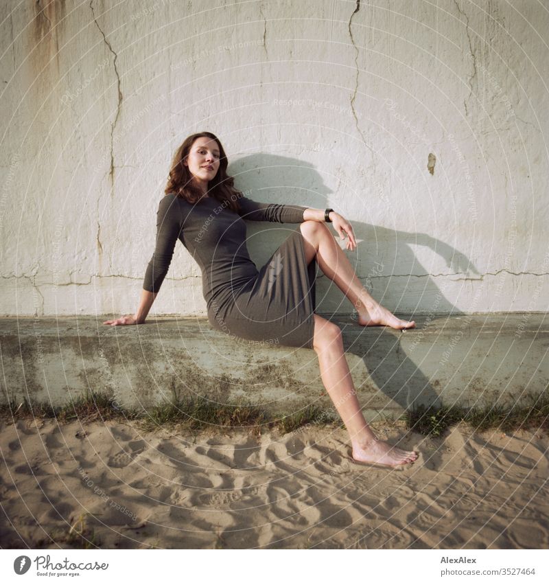 analoges Portrait einer jungen Frau im Kleid vor einer Wand Mädchen schön groß sportlich schlank fit brünett Locken langes Haar Beton Sand Strand Abend Körnung