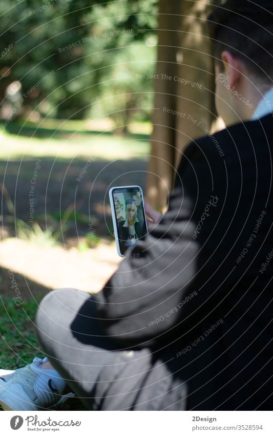 Rückenansicht eines jungen Teenagers, der auf dem Campus sitzt und ein Mobiltelefon benutzt Person Telefon Technik & Technologie Lifestyle Smartphone Mobile