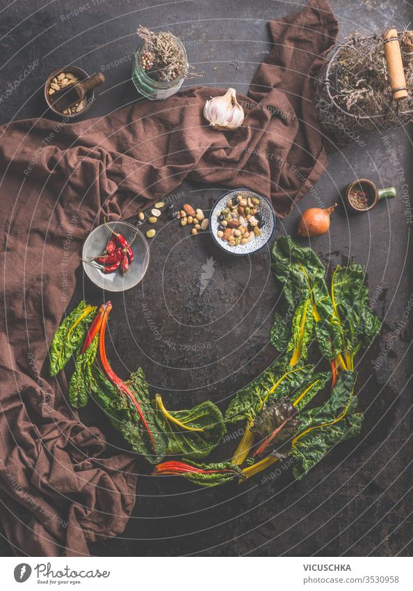 Lebensmittelhintergrund mit frischen, bunten Mangoldblättern auf dunklem, rustikalem Tischhintergrund. Hausgemachte Küche. Hintergrund farbenfroh Blätter dunkel