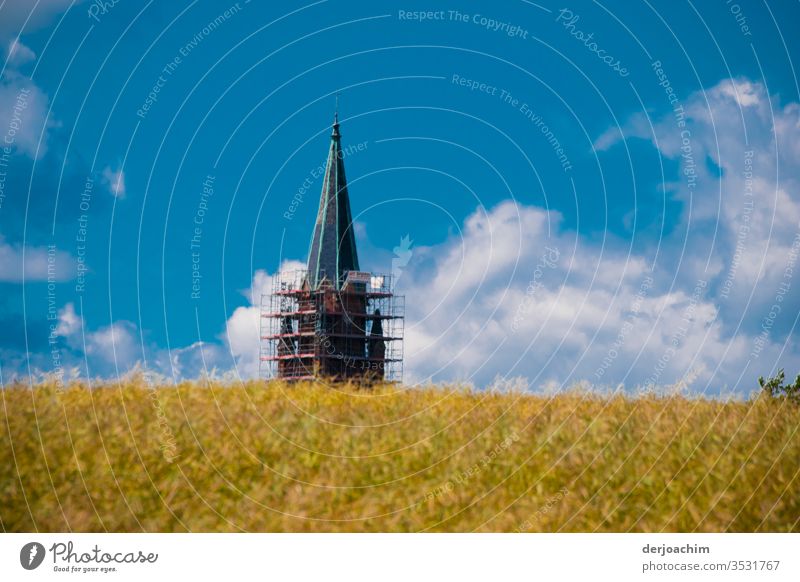 " Mein Ziel " Kornfeld mit Kirchturm.  Hinter einem Feld. Der Kirchturm hat ein Gerüst im unteren Bereich. Blauer Himmel und Wolken. Sonne Landschaft