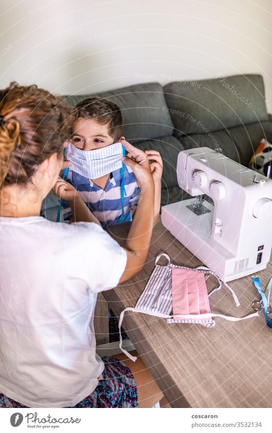 Mutter setzt ihrem Sohn eine selbstgemachte Gesichtsmaske auf Erwachsener Junge Business Kinder Kleidung Bekleidung Korona Coronavirus COVID kreativ Design