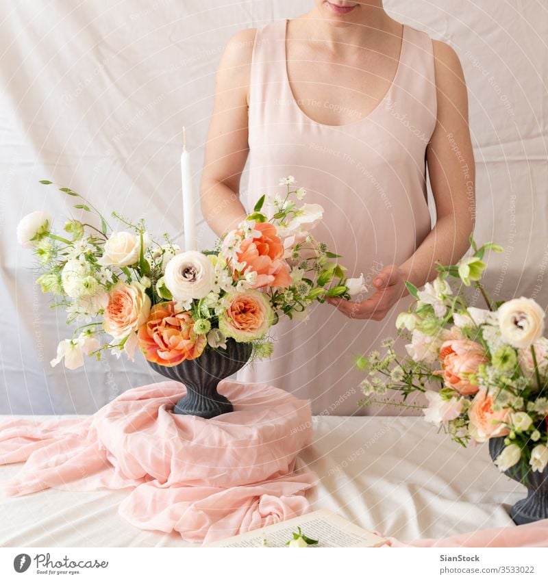 Frauenhände berühren einen Blumenstrauß. Tisch jung Kaukasier Halt Beteiligung Hände Hand Kleid weiß Vase Kerzen weich Licht Dekoration & Verzierung Hintergrund