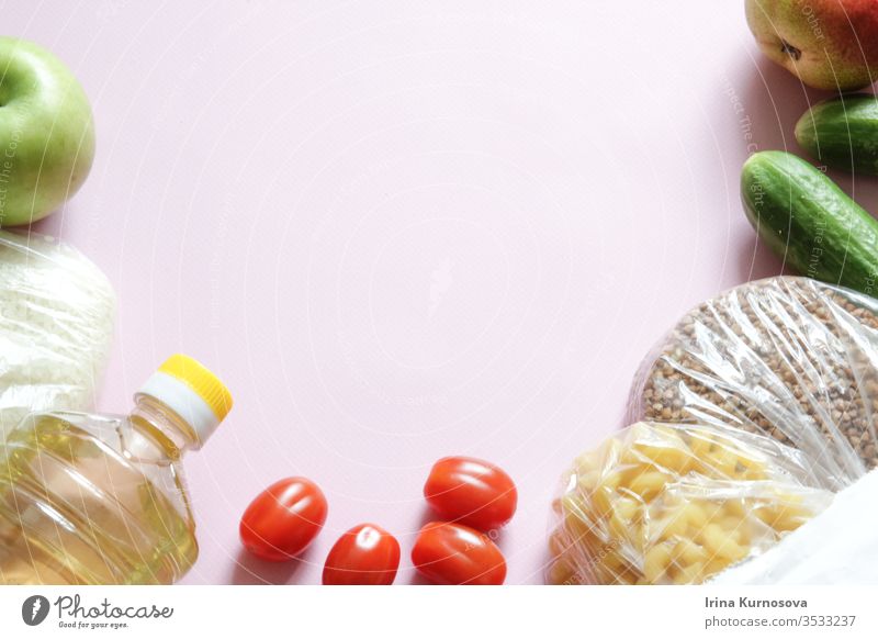 Papiertüte mit verschiedenen Naturkostprodukten auf rosa Hintergrund. Ansicht von oben. Flachgelegt mit Obst, Gemüse, Reis und Buchweizen. Apfel Tasche