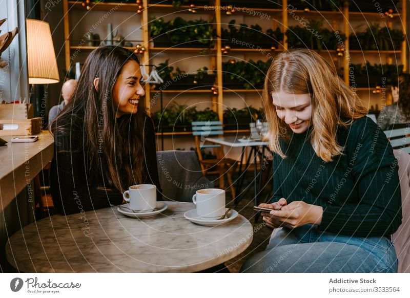 Freundinnen ruhen sich in gemütlichem Cafe aus Frauen Café Lachen Zusammensein Kaffee Smartphone benutzend Witz lässig Wochenende jung Sitzung Restaurant
