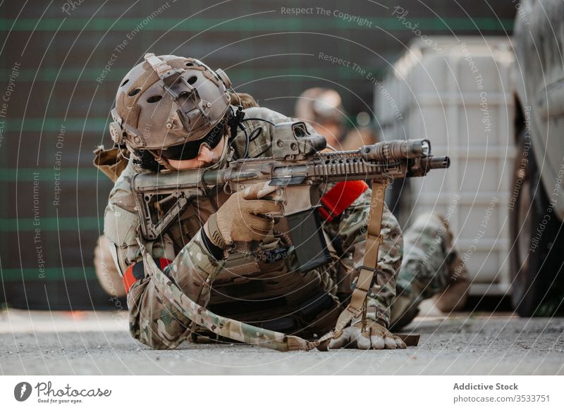 Soldat zielt mit Airsoft-Gewehr während des taktischen Spiels Mann schießen Pistole zielen Tarnung Boden Lügen männlich Uniform Militär Erwachsener behüten