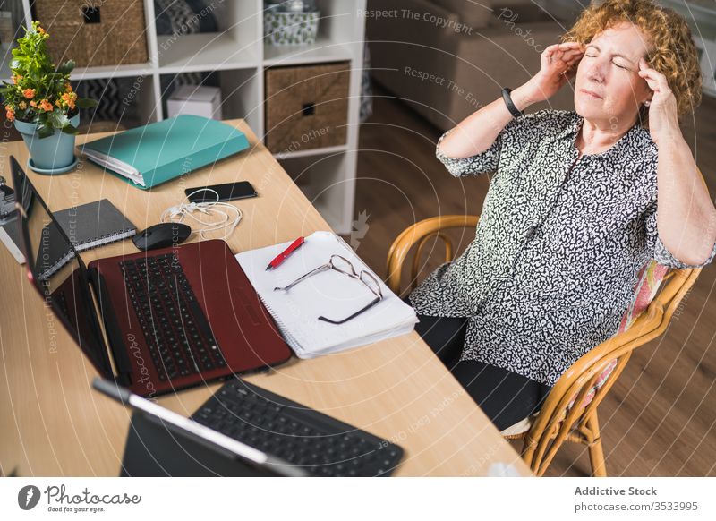 Weibliche Freiberuflerin hat Pause während der Arbeit mit Dokumenten und Geräten zu Hause Frau ruhen Kopfschmerzen müde abgelegen Entfernung Tempel reiben Stuhl