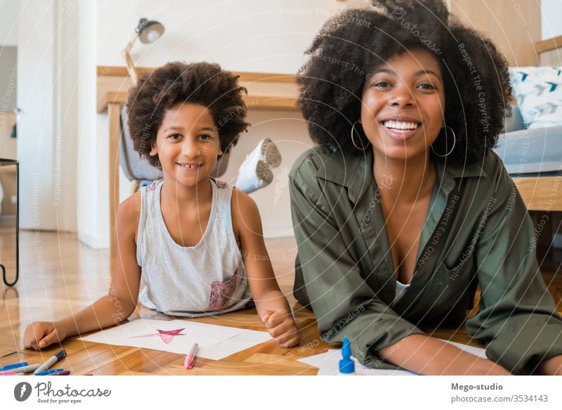 Mutter und Sohn zeichnen mit Buntstiften auf dem Boden. Spaß heimwärts Zeichnung Zusammensein Mama Schwarze Afroamerikaner gemischte Rassenfamilie
