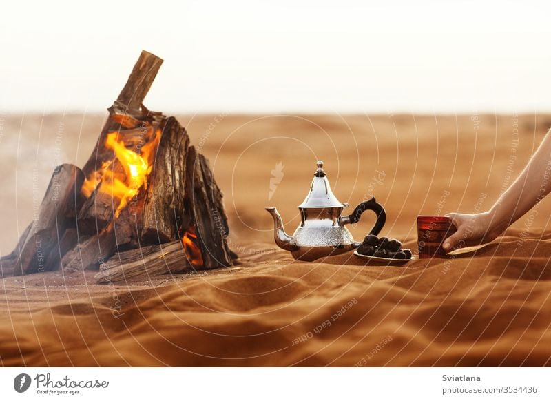 Datteln, Teekanne, Tasse mit Tee in der Nähe des Feuers in der Wüste mit einem schönen Hintergrund Daten Ramadan arabisch Kultur Kaffee Lebensmittel