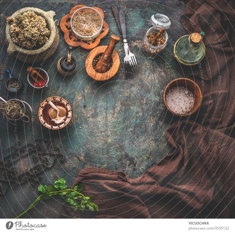 Rustikaler Hintergrund mit alten Küchenutensilien. Kräuter und Gewürze in Holzschüsseln, Olivenöl und Serviette. Rahmen. Ansicht von oben. rustikal
