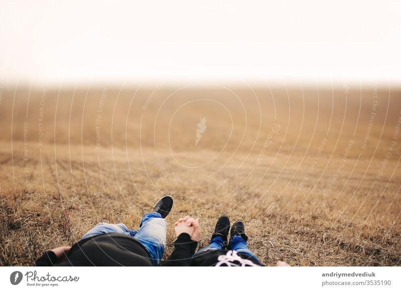 Verliebtes Ehepaar, Mann und Frau liegen im Feld und halten sich an den Händen. Begriff der Liebe. Herbstliche Stimmung. Ort für die Inschrift Menschen Sommer