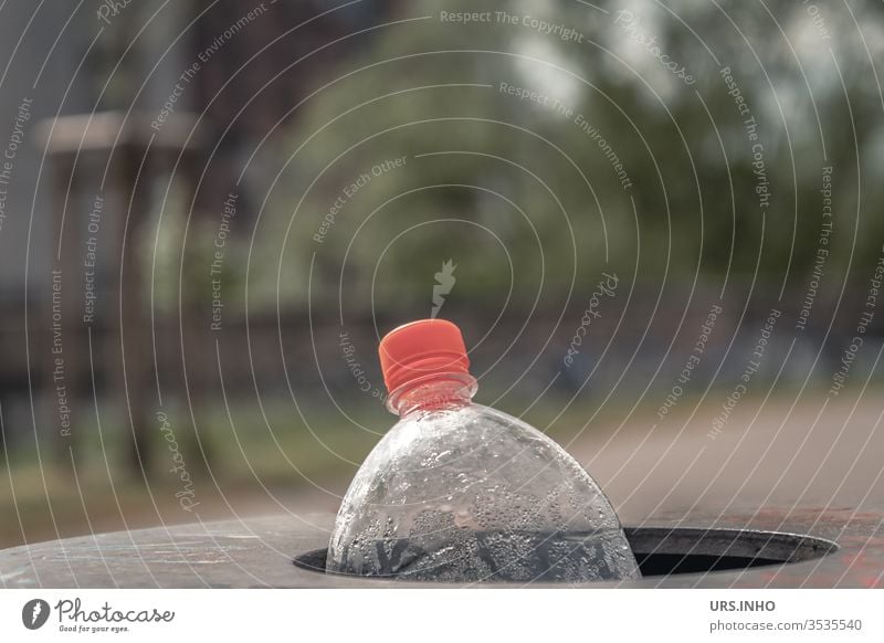 eine leere PET Flasche mit orangefarbenem Schraubverschluss wird im Papierkorb entsorgt Polyethylenterephthalat Flaschenhals wegwerfen weggeworfen Müll