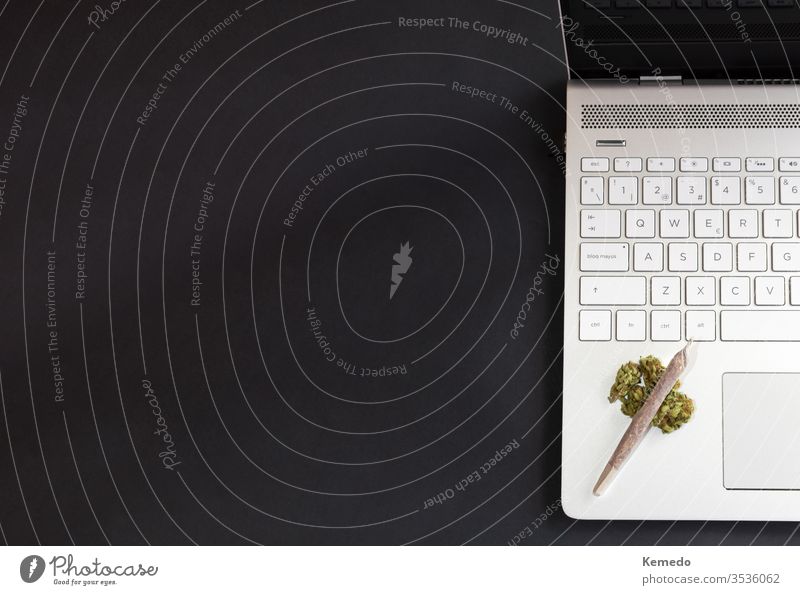 Marihuana und technologischer Hintergrund. Cannabis-Knospen und Marihuana-Gemisch auf Laptop isoliert auf schwarzem Hintergrund mit Kopierraum links.