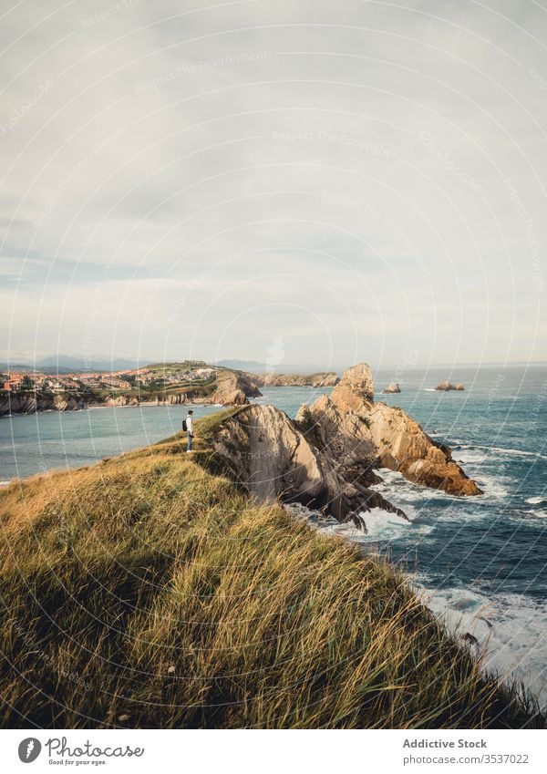 Männlicher Reisender steht im Sommer in Spanien an felsiger Meeresküste Ansicht Mann Fotoapparat Rucksack Meereslandschaft Natur Ausflug Urlaub Küste Meeresufer