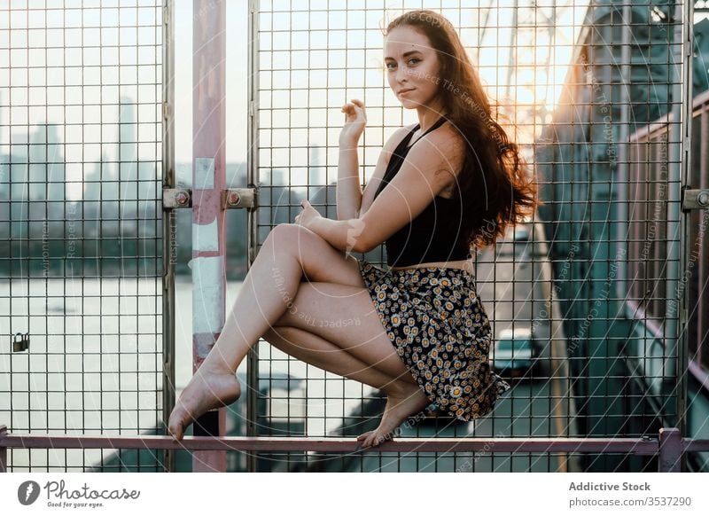 Junge Tänzerin sitzt auf dem Metallgeländer der Brücke Frau Anmut Gleichgewicht industriell urban Stadtbild Reling Barfuß jung ruhig Gelassenheit Windstille