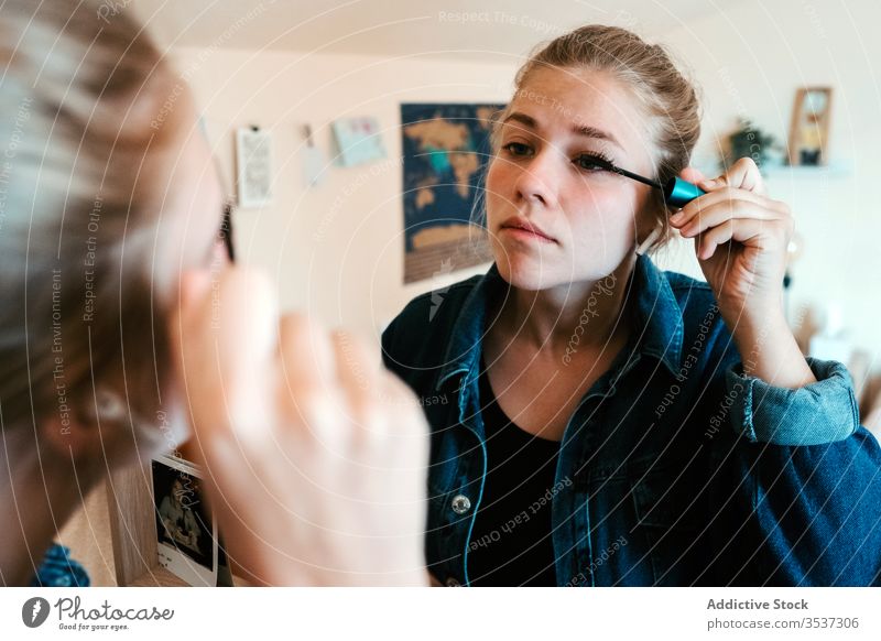 Junge Frau, die im hellen Schlafzimmer zu Hause Make-up auf die Augen aufträgt Wimperntusche Reflexion & Spiegelung heimwärts zusammenstellen Kosmetik Gesicht