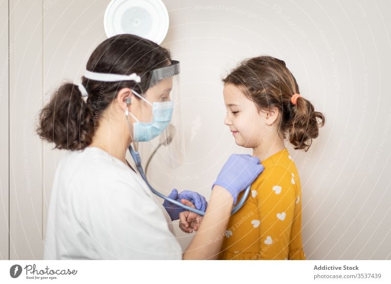 Ärztin untersucht Lungen eines kleinen Mädchens in der Klinik Frau Arzt Mundschutz geduldig Ausfallschritt Stethoskop Krankenhaus Handschuh Lungenentzündung