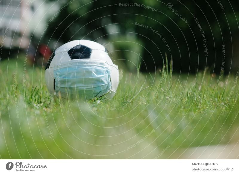 Fussball mit Gesichtsmaske für den Sport während der Covid-19-Pandemie Fußball Konzept Korona covid-19 COVID19 Gefahr Seuche Feld Spiel Gras Gesundheit Hygiene