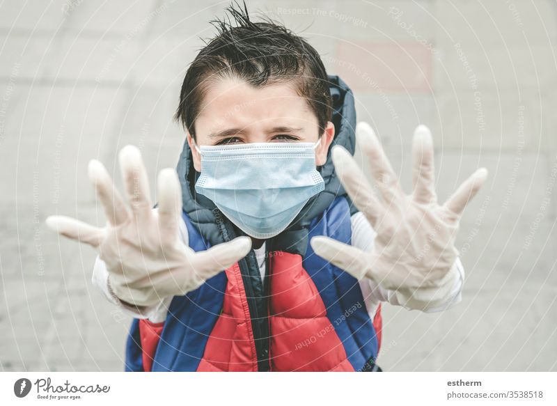 Nahaufnahme eines Kindes, das eine medizinische Maske trägt und die Hände nach oben streckt Coronavirus Virus Seuche Pandemie Quarantäne covid-19 Symptom
