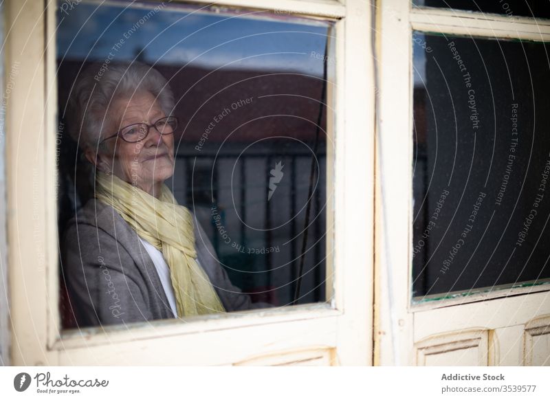 Ältere Frau schaut aus dem Fenster Senior Coronavirus heimwärts einsam Anspannung verzweifelt unglücklich traurig Quarantäne verhindern alt behüten allein