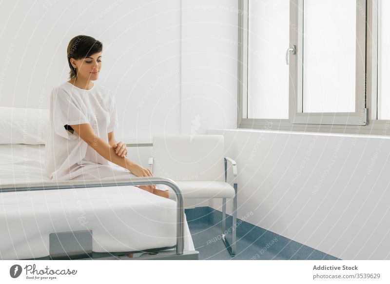 Positive Patientin sitzt im Krankenhaus auf dem Bett Frau geduldig Station positiv Robe modern Licht weiß froh Freude Klinik Glück ruhen sich[Akk] entspannen