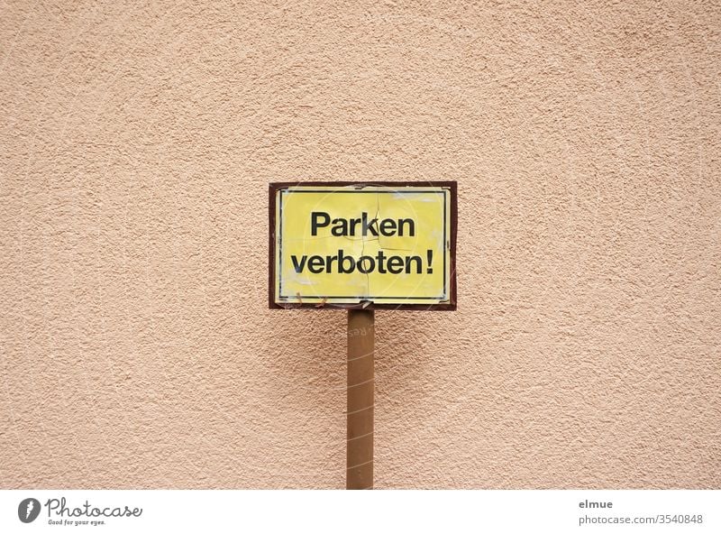 gelbes Schild mit schwarzer Schrift Parken verboten! vor einer