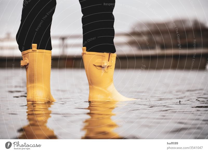 gelbe Gummistiefel stehen auf der überfluteten Promenade Hochwasser Klimawandel Überflutet hochwasserlage Umwelt globale Erwärmung Weser Meer Wasser Landschaft