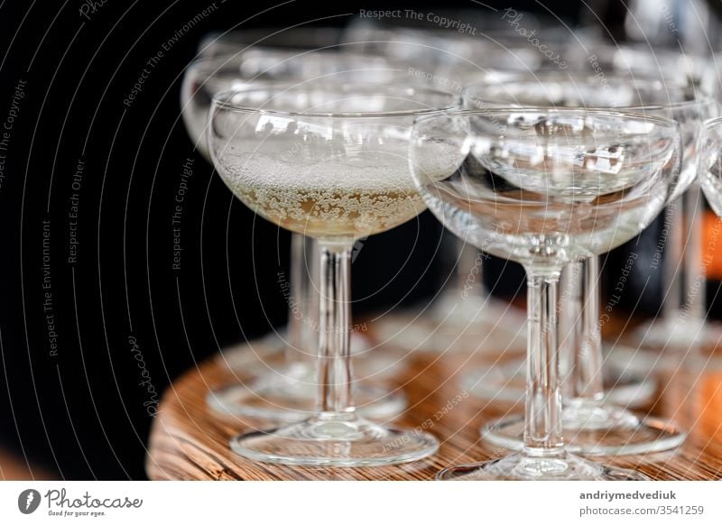 Sekt, Champagner in Gläsern auf dem Holztisch auf schwarzem Hintergrund im Restaurant. Glas Hand Kellnerin Catering Menschengruppe Handschuhe offen Party Person
