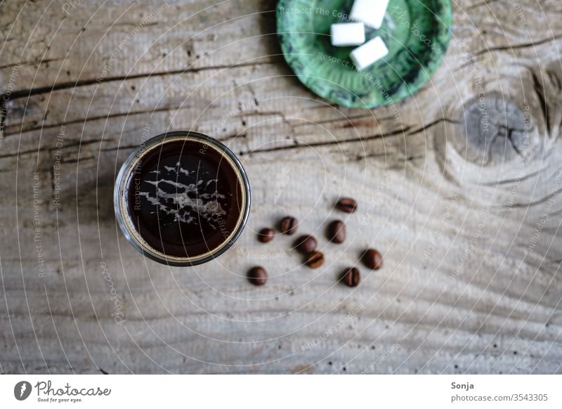 Kaffee in einem Glas und Würfelzucker auf einem grünen Teller. Rustikaler Holztisch, Draufsicht. Getränk Espresso glastasse stark aromatisch Koffein Früstück