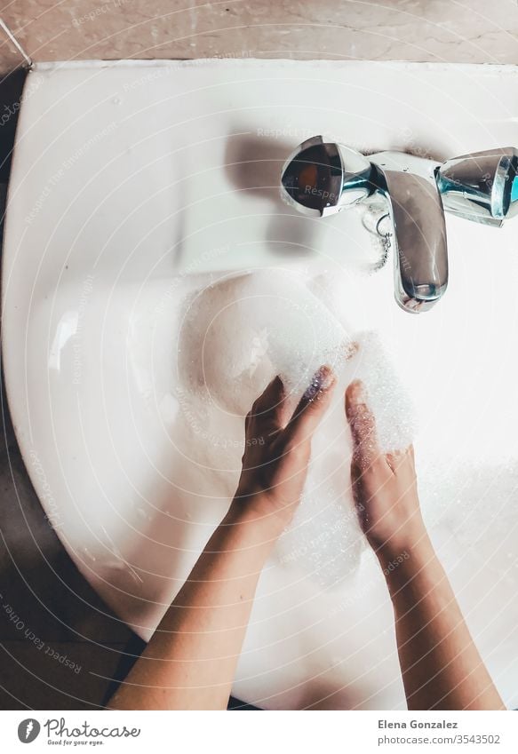 Frau wäscht ihre Hände im Badezimmer, um eine Covid-19-Infektion zu verhindern. Empfohlenes Waschen mit Seife und fließendem Wasser während einer Coronavirus-Pandemie. Ansicht von oben