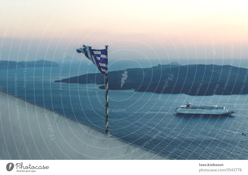Zerrissene griechische Flagge entlang der Sonnenuntergangsküste mit Kreuzfahrtschiff in Fira, Santorin, Griechenland Fahne gerissen Sommer Himmel reisen Meer