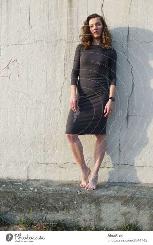 Porträt einer jungen Frau vor einer Betonmauer am Strand Mädchen schlank brünett Locken lange Haare Abend 18-25 Jahre Jugendliche Junge Frau Erwachsene Haut