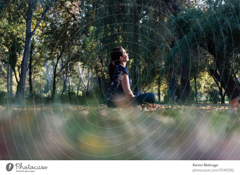 Schöne Frau sitzt auf Gras vor der Sonne und macht Yoga Rücken Gleichgewicht Konzentration Übung passen Fitness Lotos meditieren meditierend Meditation mental