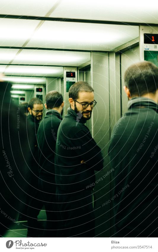 Ein Mann, der sich mehrmals in den Spiegeln eines Fahrstuhls spiegelt Brille Spiegelung Persönlichkeiten Multiple Persönlichkeit unendlich ernst