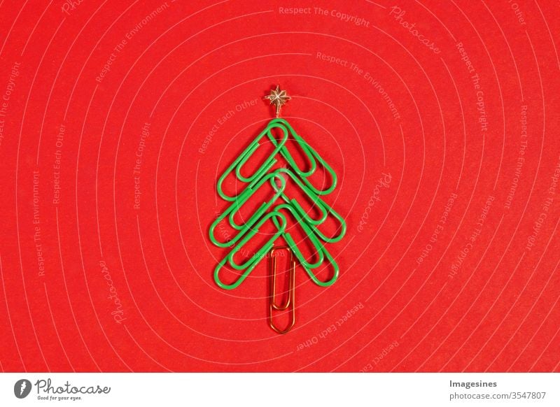 Frohe Weihnachten im Büro. Weihnachtsbaum aus Büroklammern auf dem roten Hintergrund. Büroklammer Weihnachtsbaum. Weihnachtshintergrund. Textfreiraum rechts