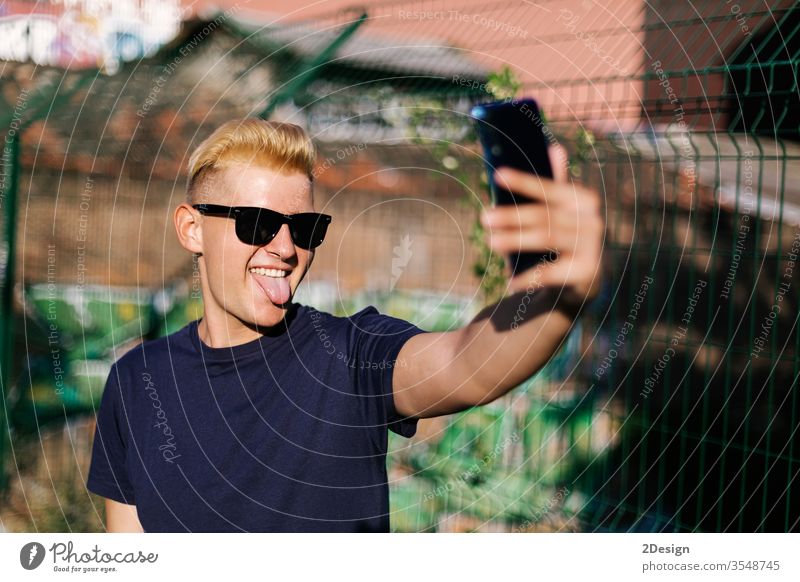 Junger Teenager mit Sonnenbrille bei einem Selbstversuch im Freien männlich jung Selfie Telefon 1 Mann Person benutzend Porträt Smartphone modern Beteiligung
