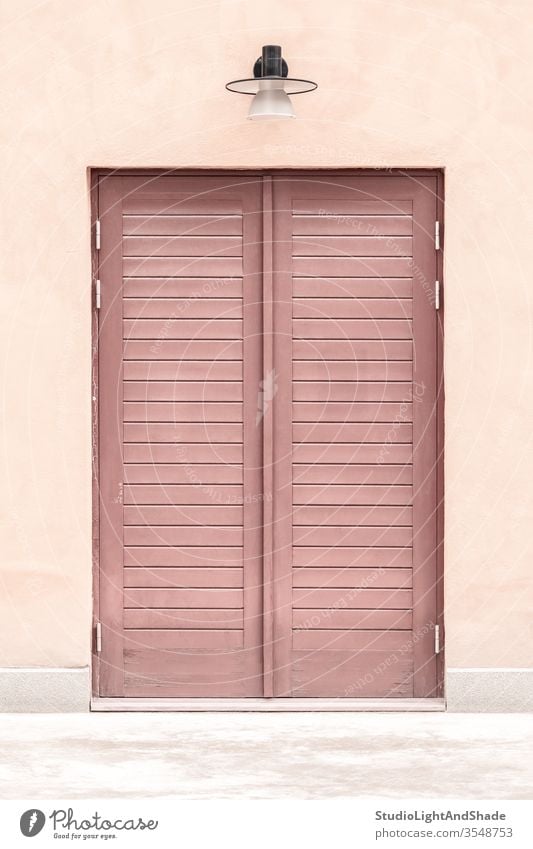 Rosa Gebäude mit einer Holztür Tür Eingang rosa rot Pastell zugeklappt hölzern Haus heimwärts Lampe Straßenlaterne Außenseite Großstadt Stadt urban Europa