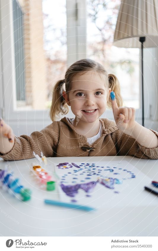 Kleines Mädchen zeigt Finger mit Gouache beim Zeichnen im Wohnzimmer Farbe Papier zeigen zeichnen Punkt spielerisch niedlich Vorschule Zeichnung abstrakt Bild