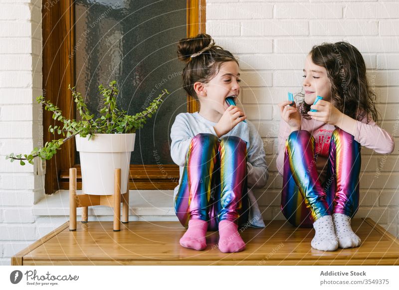 Fröhliche kleine Mädchen essen blaue Kaubonbons Kauen Bonbon Leckerbissen süß teilen heimwärts Spaß Glück Kinder geschmackvoll Lachen lecker Schwester Pyjama