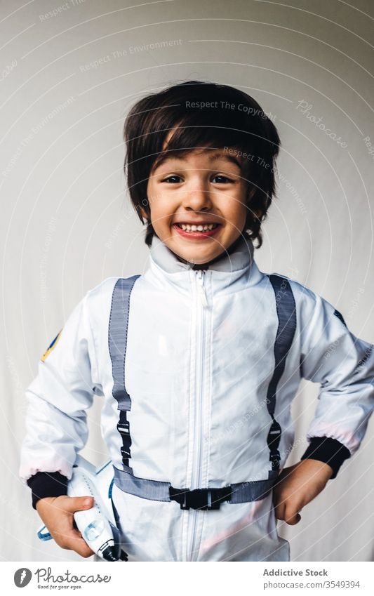 Bezaubernder ethnischer Junge im Kosmonautenkostüm auf weißem Hintergrund Tracht bezaubernd Raumfahrer Spielzeug Raumschiff positiv Kind Astronaut Spaß haben