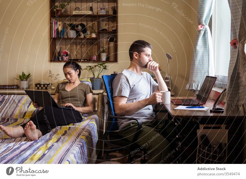 Multiethnische Freiberuflerpaare nutzen Laptops im Heimbüro Paar freiberuflich Arbeit heimwärts Büro Browsen beschäftigt Unternehmer benutzend