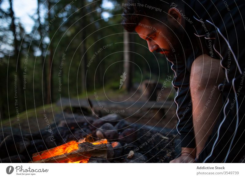 Männlicher Reisender in der Nähe eines Lagerfeuers im Wald Freudenfeuer Mann ruhig Wohnmobil Wälder Aufwärmen genießen männlich Wochenende Abend