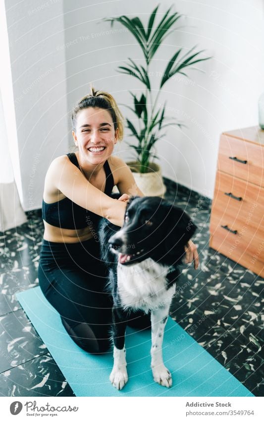 Frau hat Spaß mit Hund während der Yoga-Stunde zu Hause heimwärts Spaß haben Lächeln Begleiter Freund Umarmung Zusammensein Besitzer Reinrassig üben Haustier