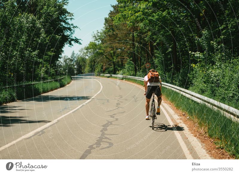 Ein Mann fährt auf einem Fahrrad auf der Straße bergauf. Fahrradfahren. Ausflug. Sommer Radfahren draußen Sonne Hügel Steigung hoch Sport Natur Lifestyle