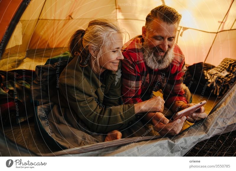 Glückliches älteres Paar mit Telefon im Zelt auf dem Campingausflug Smartphone Technik & Technologie Lächeln verbunden Internet Browsen online genießend aktiv