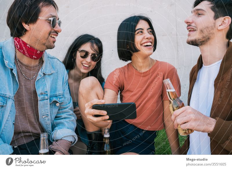 Gruppe von Freunden, die sich etwas auf einem Smartphone ansehen. Mobile Telefon Freundschaft Lifestyle Porträt Beteiligung urban modern Sitzung Freude Genuss
