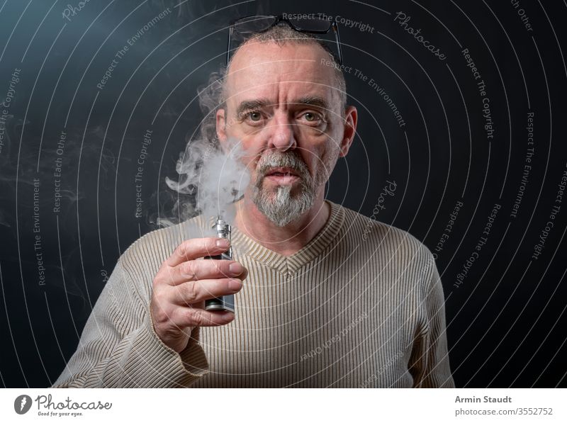 Porträt eines Mannes mit Bart, der sich gerade windet Hintergrund Vollbart blasend Unschärfe Zigarette Zigaretten selbstbewusst cool E-Zigarette ecig