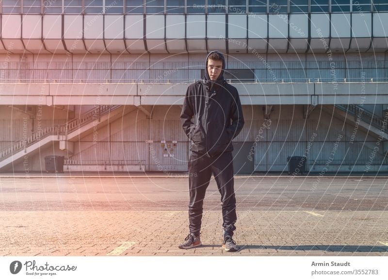 Porträt eines jungen Mannes mit schwarzem Kapuzenpulli Jugendlicher Architektur schön Junge Gebäude lässig Kaukasier selbstbewusst eifrig Lifestyle Blick